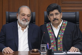 Vista frontal de Carlos Slim, a la izquierda con traje oscuro y camisa blanca, junto a Hugo Aguilar Ortiz, a la derecha con toga negra y estola colorida, sentados en un despacho.