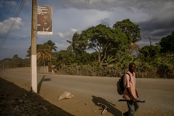 FILE Ñ A field worker walks past a poster showing HaitiÕs assassinated president Jovenel Mose in Cap-Hatien, Haiti, Sept. 15, 2021. The Justice Department on Sunday, Sept. 20, 2026, arrested an additional 30 suspects in the 2021 assassination of Haitian president Jovenel Mose, including 18 who had been transferred from Haiti to Miami aboard a U.S. military plane, according to the U.S. attorney for South Florida. (Adriana Zehbrauskas/The New York Times)