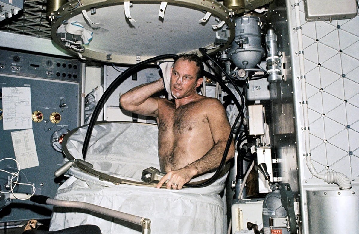 El astronauta Jack Lousma se asea en el compartimento de ducha dentro del módulo espacial. (NASA)