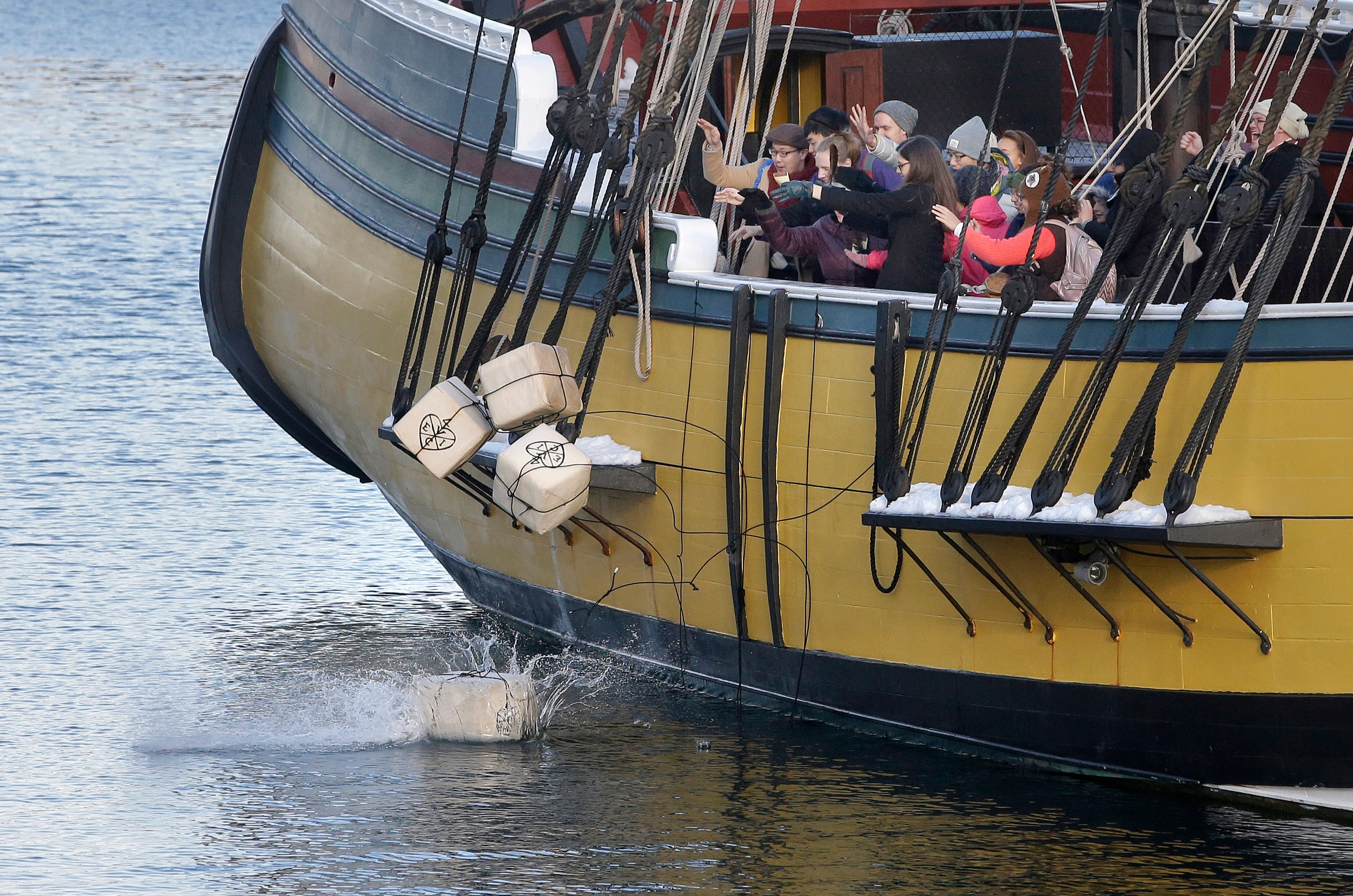 ARCHIVO-En esta foto del lunes 11 de diciembre de 2017, visitantes del Museo del Motín del Té de Boston lanzan réplicas de históricos contenedores de té desde una réplica del buque Beaver, en Boston (AP Foto/Steven Senne)