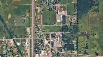 Mapa satelital de Warner con Warner High School y Warner Elementary School marcadas con chinchetas rojas. Incluye carreteras, edificios, campos verdes, un campo de béisbol y un campo de fútbol