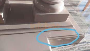 La base de madera de una mesa con una grieta resaltada dentro de un círculo azul sobre un piso entablonado