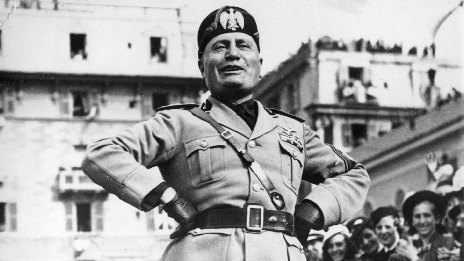 8 de mayo de 1938: El dictador italiano Benito Mussolini (1883-1945) se encuentra en una plataforma mientras se dirige a los obreros de una fábrica de municiones en Génova, Italia. Está rodeado por sus tropas. (Foto de New York Times Co.)
