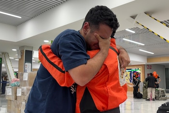 German Bello, derecha, voluntario de la brigada mexicana de búsqueda y rescate Topos Azteca, abraza a un venezolano que se acercó al equipo para agradecerles mientras salían para Venezuela desde el Aeropuerto de Ciudad de México, el martes 30 de junio de 2026. (AP Foto/Fernanda Pesce)