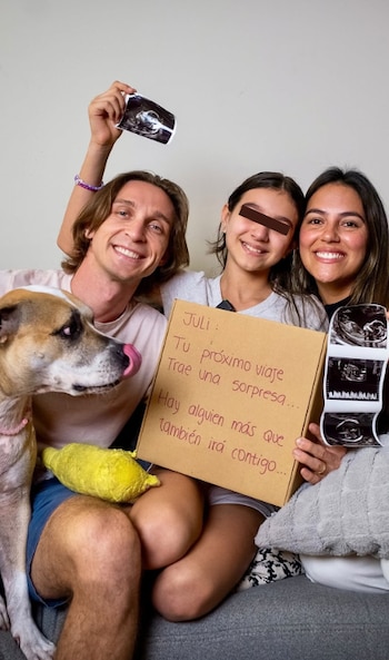 Sasha Kapsunov sonríe junto a su esposa, su hija Julieta y un perro, mientras muestran ecografías y un cartel anunciando un embarazo