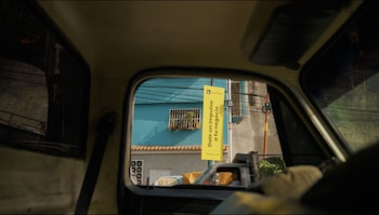 Vista desde el interior de un vehículo con un banner amarillo de Cashea que muestra el texto "Dale un impulso a tu negocio", un edificio azul y cables aéreos