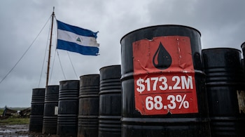 Barriles de petróleo apilados bajo un cielo gris, uno con etiqueta roja mostrando cifras '$173.2M' y '68.3%'. Al fondo, la bandera de Nicaragua ondea.