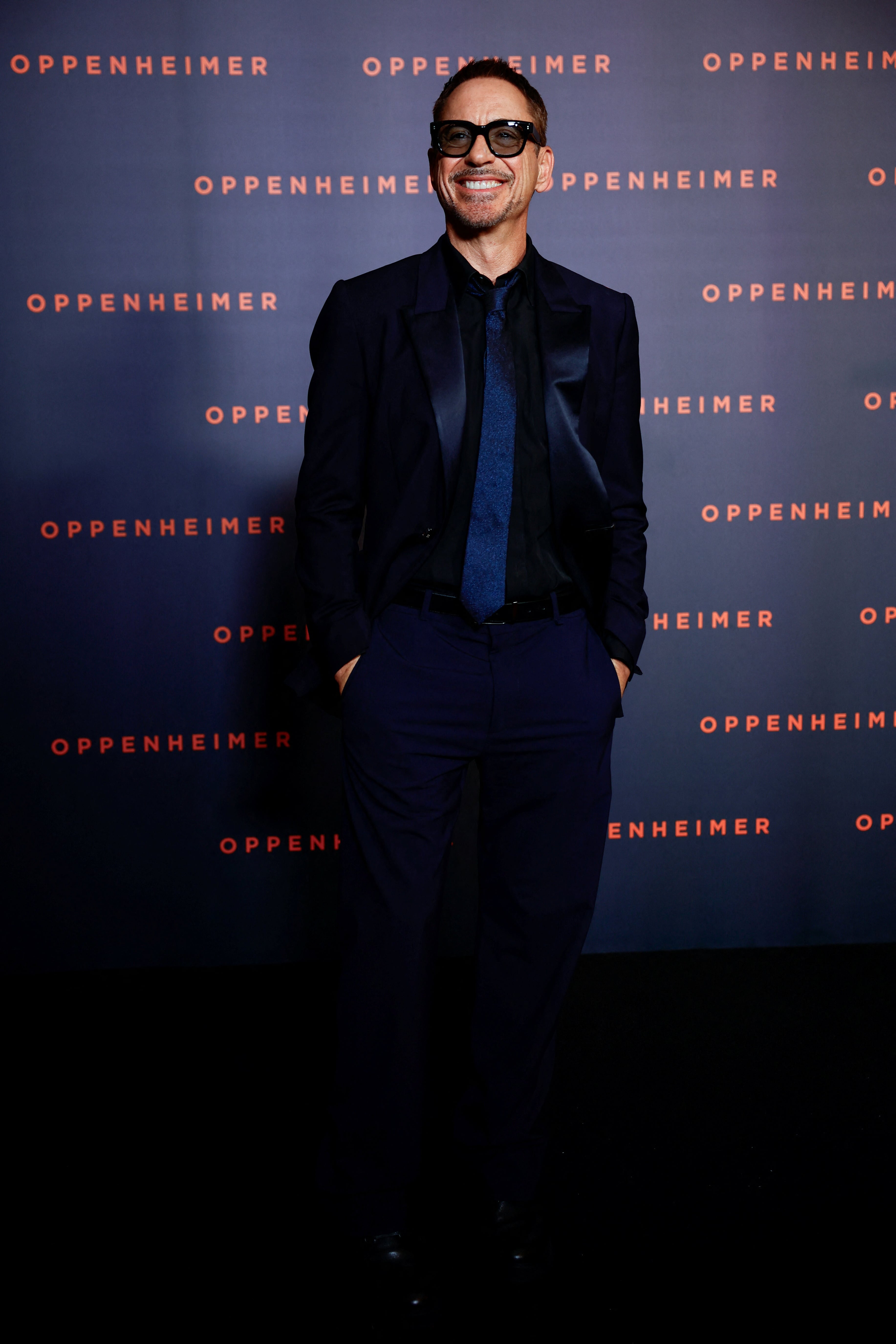Traje azul oscuro de corte clásico, camisa negra y corbata azul texturizada en la presentación de “Oppenheimer”(REUTERS/Sarah Meyssonnier)