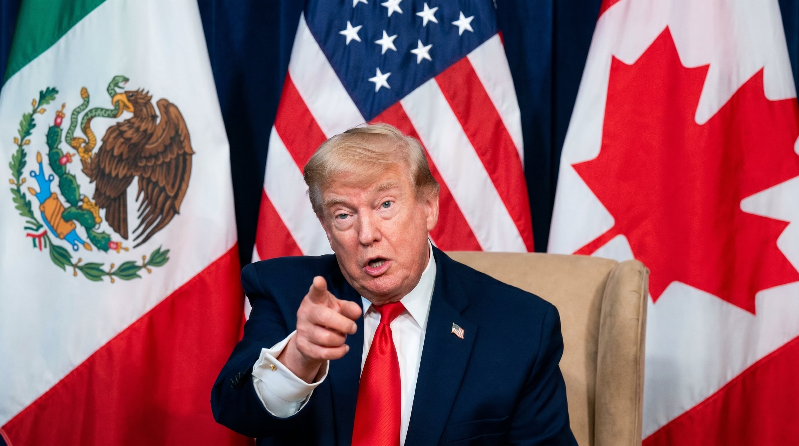 Donald Trump, con las banderas de México, Estados Unidos y Canadá como telón de fondo, se dirige a los presentes con un gesto enfático, subrayando la importancia de la colaboración trilateral en Norteamérica. (Imagen Ilustrativa Infobae)