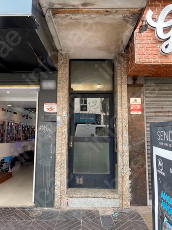 Un panel de vidrio fisurado y roto muestra grietas profundas y deja ver un automóvil gris estacionado frente a un edificio