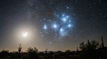 Cielo nocturno con cúmulo estelar de las Pléyades, miles de estrellas, Luna creciente y paisaje desértico con cactus y montañas en el horizonte.