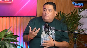 Hombre de tez morena y camisa verde con logo de Hugo Boss habla frente a un micrófono en estudio, con plantas y pantalla iluminada al fondo
