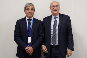 Luis Caputo e Ilan Goldfajn de pie con trajes oscuros y corbatas frente a una pared blanca