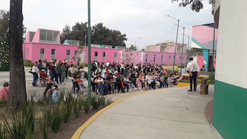 Multitud de personas sentadas y de pie en un espacio abierto viendo a un artista de espaldas. Al fondo, edificios rosas y un árbol de Navidad a la izquierda