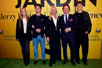 Cinco personas, tres jóvenes y dos adultos, posan sonrientes en el estreno de 'Desde el jardín', frente a un cartel amarillo y una alfombra verde
