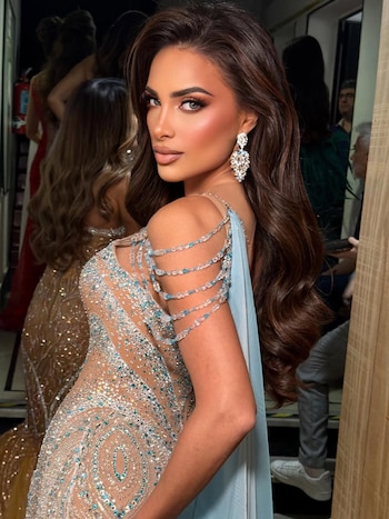 Tamara Rogouski, con cabello castaño ondulado, mira a cámara. Lleva un vestido nude con pedrería plateada y turquesa, y pendientes colgantes brillantes