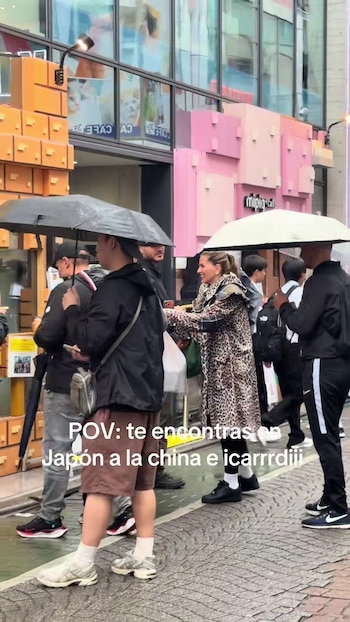 La China Suárez, con abrigo de estampado animal, camina bajo la lluvia en una calle concurrida de Japón junto a otras personas, algunas con paraguas