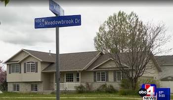 Una casa residencial beige con techo marrón y césped verde, con un cartel de calle azul que muestra '900 W Meadowbrook Dr' y '830 S Mallard Ln' en primer plano
