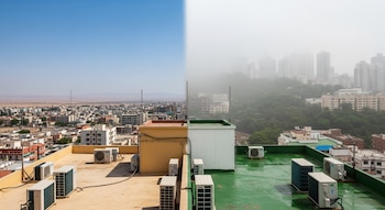 Vista aérea de dos ciudades divididas: una con cielo azul y desierto, otra con niebla y edificios altos. Azoteas con unidades de aire acondicionado.