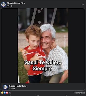 Un hombre sonriente con cabello gris abraza a un niño de cabello rizado pelirrojo que lleva una camiseta roja y sostiene un objeto