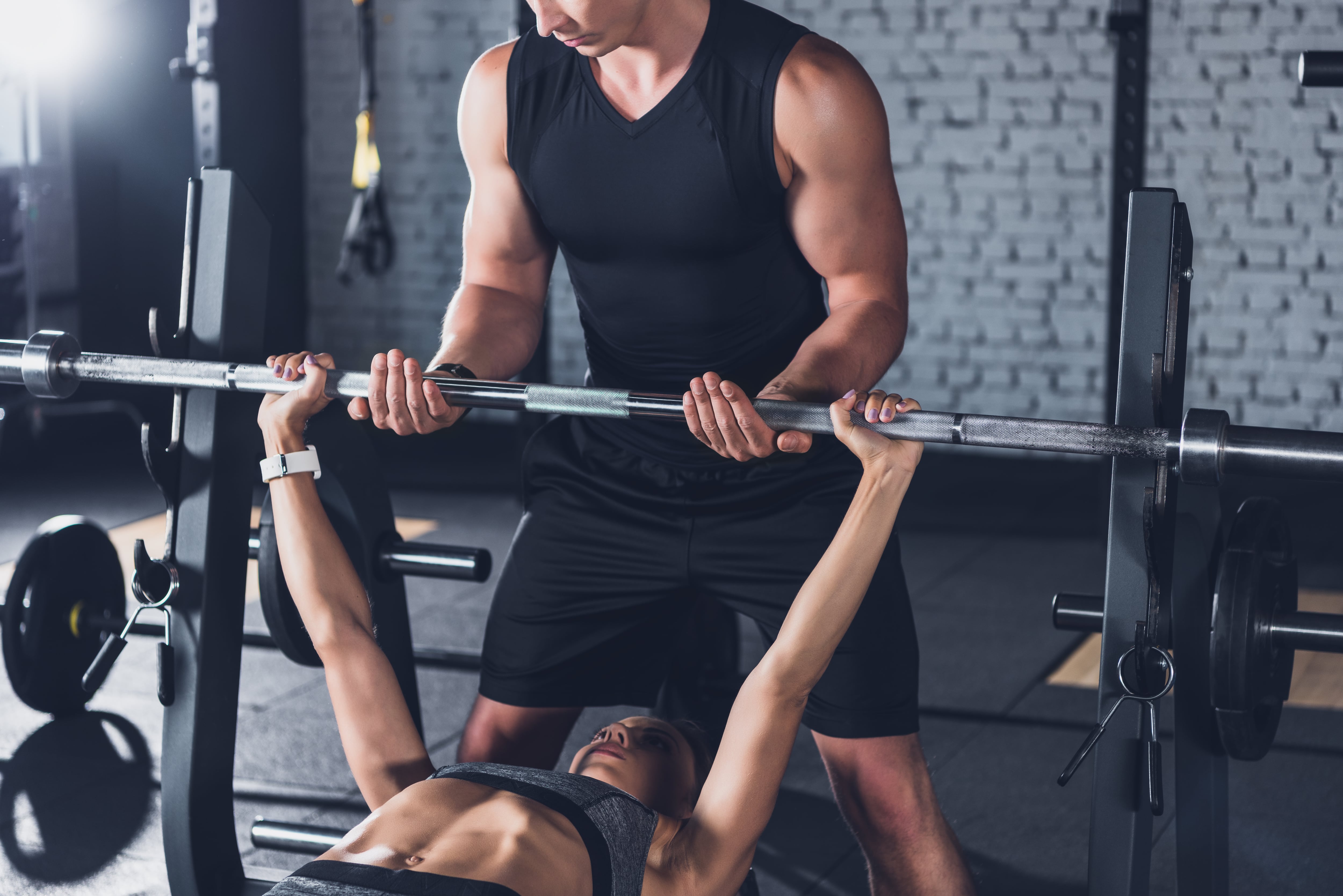 Una mujer levantando pesas en el gimnasio (AdobeStock)