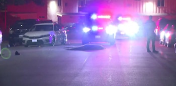 Calle nocturna con patrullas policiales con luces de emergencia encendidas y una lona sobre el asfalto