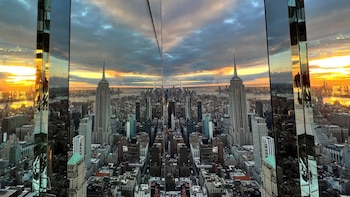 Ciudad de Nueva York al atardecer desde One Vanderbilt. El Empire State Building y rascacielos se reflejan en las paredes de espejo, con un cielo vibrante