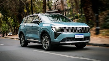 SUV Ford Territory Platinum azul claro en movimiento. Frente del vehículo visible, con árboles al fondo y efecto de velocidad en las ruedas