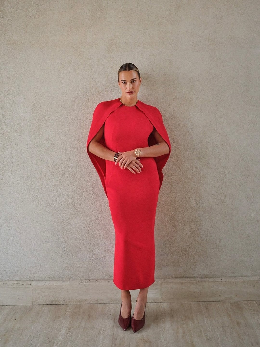 La tenista Aryna Sabalenka posa con un impactante vestido rojo y capa, complementado con tacones a juego, mostrando su estilo fuera de la cancha (@arynasabalenka)