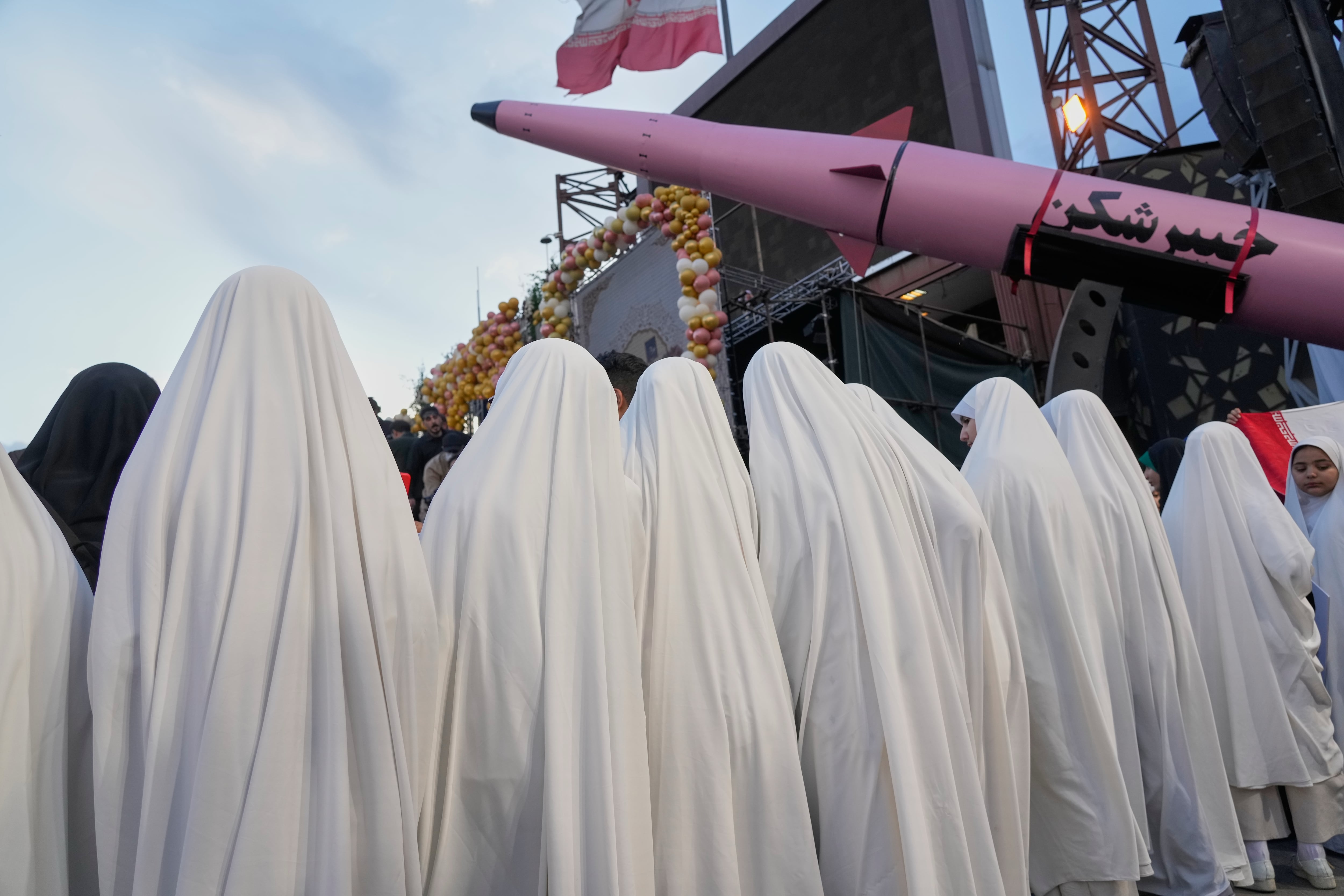 Un grupo de mujeres posa junto a un misil Khaybar-buster durante una boda colectiva de parejas que participan en la campaña pro régimen Janfada (Sacrificio por Irán) en Teherán, Irán, el lunes 18 de mayo de 2026 (AP/Vahid Salemi)