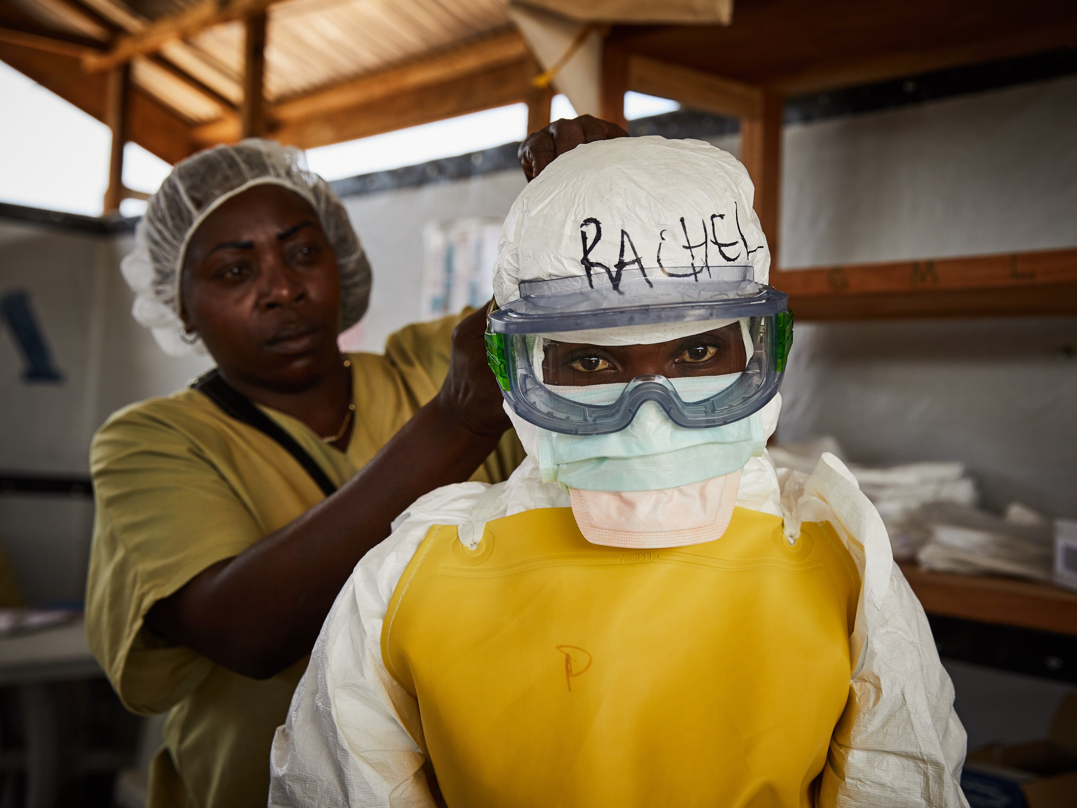 Un par de trabajadoras de la salud fueron captadas el pasado 12 de mayo al ataviarse con equipos de protección personal, antes entrar en una zona de tratamiento de alto riesgo de propagación del virus del ébola, en un centro de salud en Beni, Kivu del Norte, República Democrática del Congo. EFE/Hugh Kinsella