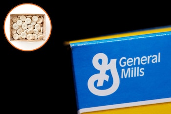 Una caja de madera con panecillos redondos claros y el logotipo de General Mills en un envase azul y amarillo