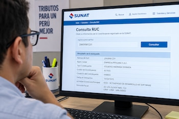 Persona frente a un monitor de computadora que muestra el sitio de la SUNAT con los datos de un número de RUC
