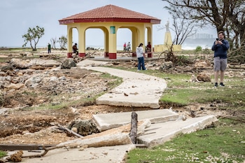 Un hombre toma fotografías de la destrucción en Guam (Yuichi YAMAZAKI / AFP)