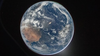 Imagen del planeta Tierra desde el espacio, mostrando África y Europa, océanos azules, nubes blancas y una estela luminosa sobre el Atlántico