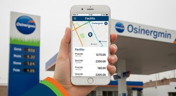 Una mano sostiene un smartphone con la app Facilito mostrando precios de combustible y mapa; al fondo, un letrero y marquesina de estación Osinergmin.