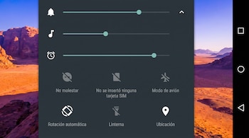 Captura de pantalla de un dispositivo Android mostrando el panel de control de volumen y ajustes rápidos en gris oscuro sobre un fondo de desierto.