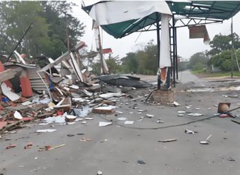 Una estructura derrumbada con pedazos de hormigón, láminas de metal y escombros dispersos en una calle asfaltada