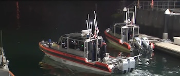 Dos lanchas de la Guardia Costera de Estados Unidos navegan de noche cerca de un embarcadero en aguas oscuras