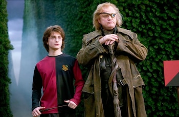 Daniel Radcliffe como Harry Potter con una varita y Brendan Gleeson como Alastor Moody con un ojo mágico de pie frente a un seto verde