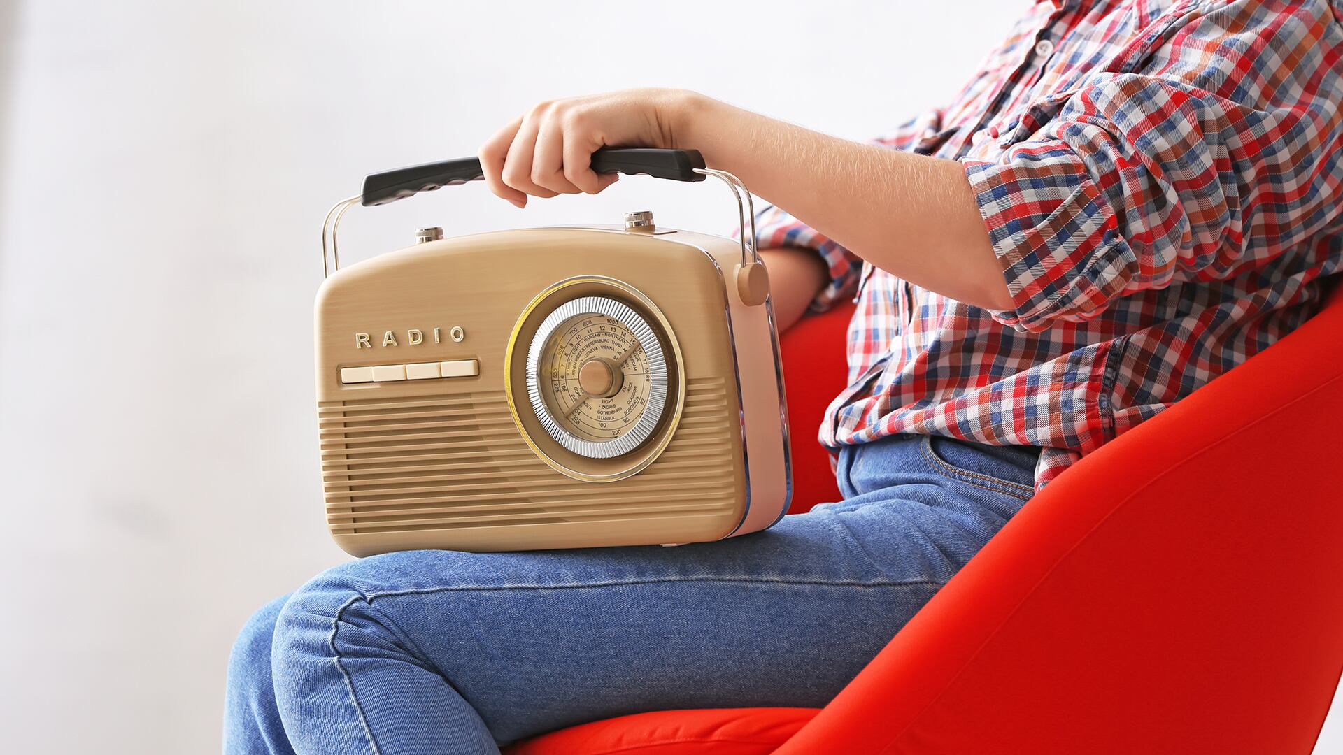 Young woman with retro radio sitting on light background (Freepik)