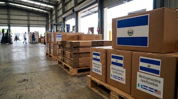 Pallets con cajas de cartón apiladas en una bodega. Algunas cajas muestran banderas de El Salvador, Guatemala, Honduras, Nicaragua y Estados Unidos.
