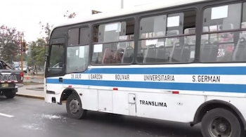 Un autobús blanco y azul con el texto Translima en un carril de circulación junto a una patrulla de policía.