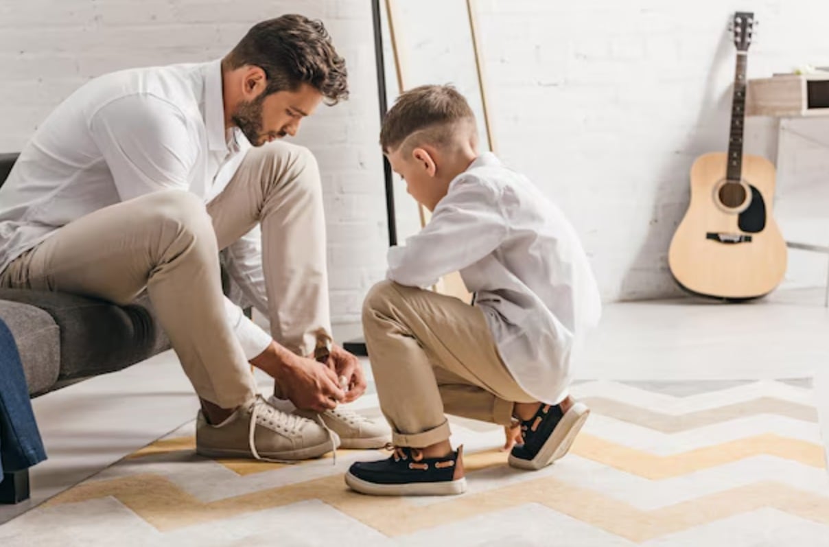 Un niño observa cómo su padre se ata los cordones. (Freepik)