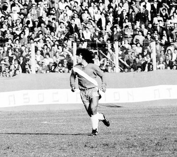 Fotografía en blanco y negro de un futbolista en un campo de juego con una multitud sentada en las gradas del fondo