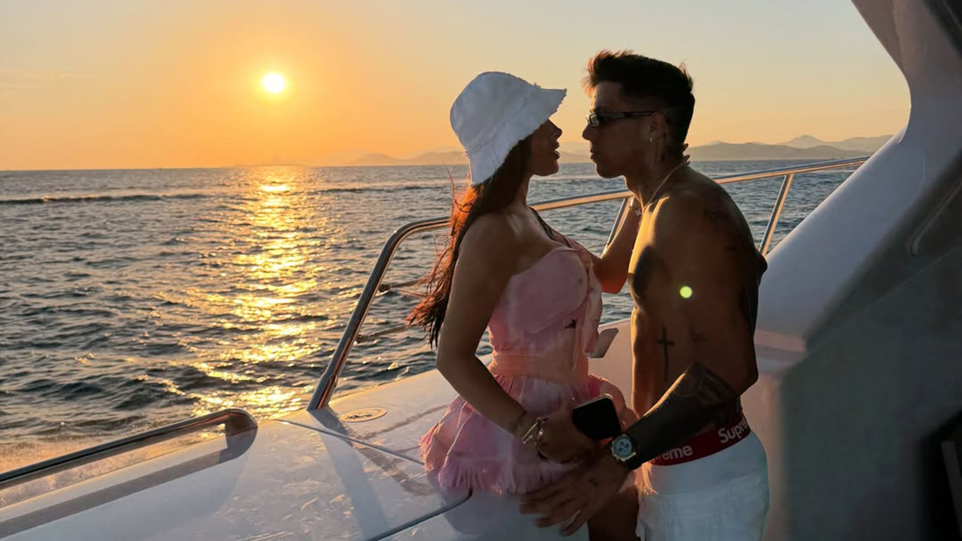 Enzo Fernández y Valentina Cervantes posan en un yate durante un atardecer sobre el mar