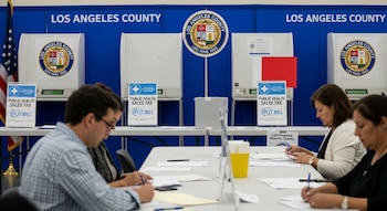 Centro de votación del Condado de Los Ángeles: cabinas, urnas electrónicas, mesas con papeletas, y votantes no identificables. Logotipos del condado y folletos de impuesto de salud.