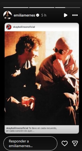 Fotografía vintage de Skay Beilinson sonriendo y sosteniendo un vaso, junto a Indio Solari con gafas de sol oscuras y tocándose la barbilla