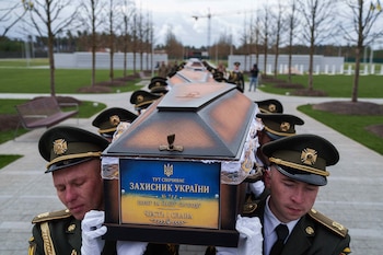 Una guardia de honor carga con los féretros de soldados ucranianos no identificados muertos en batalla durante la guerra entre Rusia y Ucrania en un funeral en un cementerio militar cerca de Kiev (AP Foto/Evgeniy Maloletka, archivo)