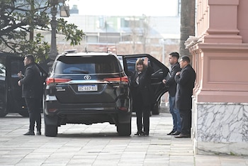 Patricia Bullrich saluda con la mano extendida al salir de una camioneta negra junto a la Casa Rosada y personal de seguridad